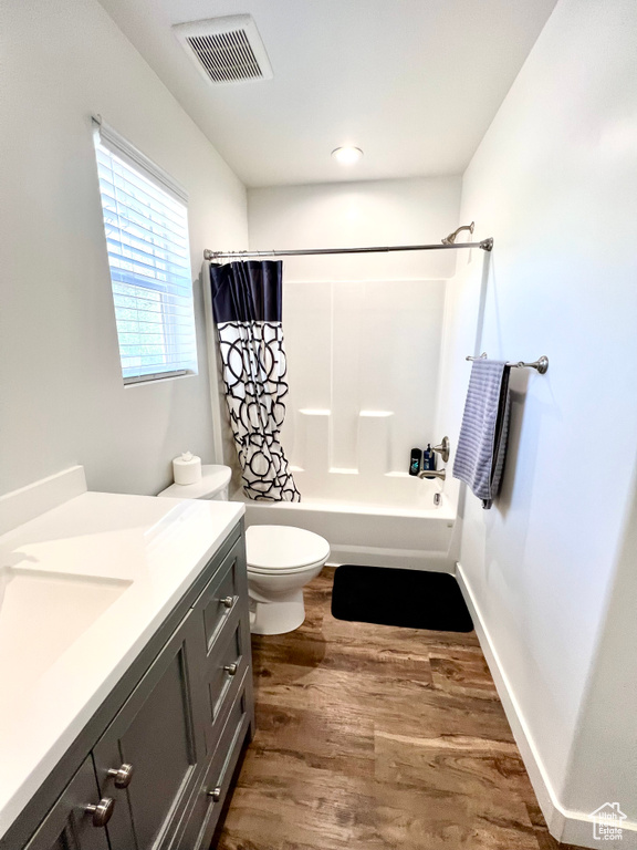 Bathroom featuring toilet, shower / tub combo with curtain, visible vents, vanity, and wood finished floors