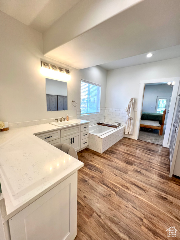 Bathroom with a garden tub, a wealth of natural light, ensuite bathroom, and wood finished floors
