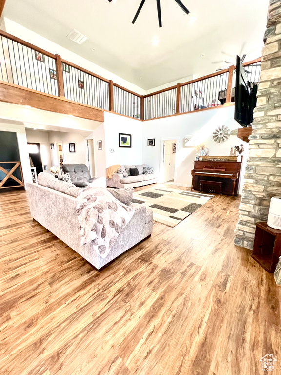 Living room featuring a towering ceiling, wood finished floors, and a ceiling fan