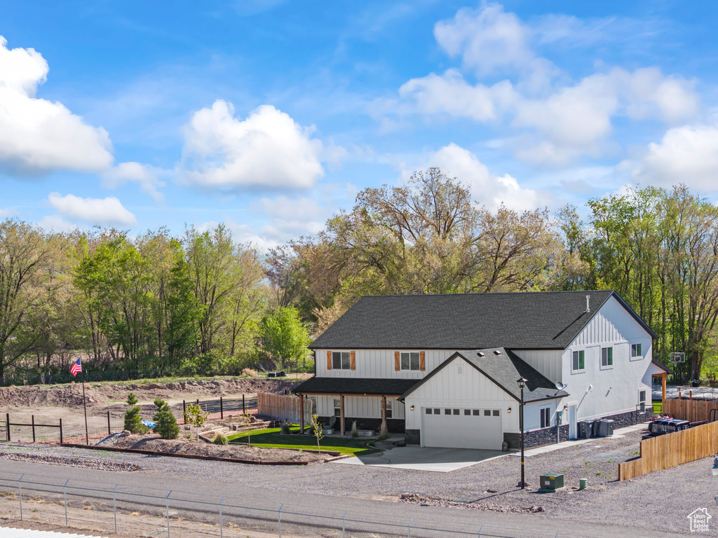 View of front of house featuring board and batten siding, fence, a garage, a shingled roof, and concrete driveway