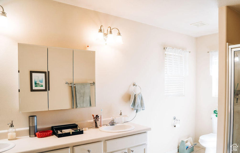 Full bathroom with toilet, an enclosed shower, double vanity, and a sink