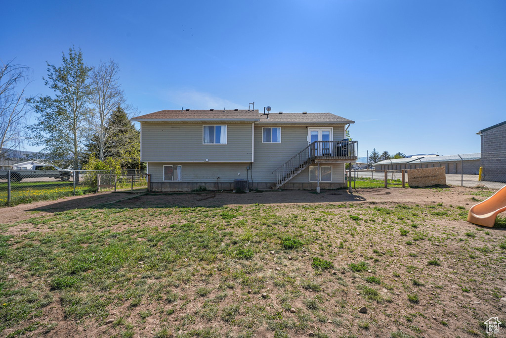 Back of property featuring a lawn, fence, stairs, a deck, and a playground