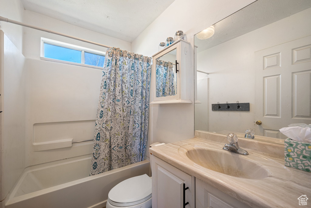 Full bathroom featuring toilet, shower / bath combo, and vanity