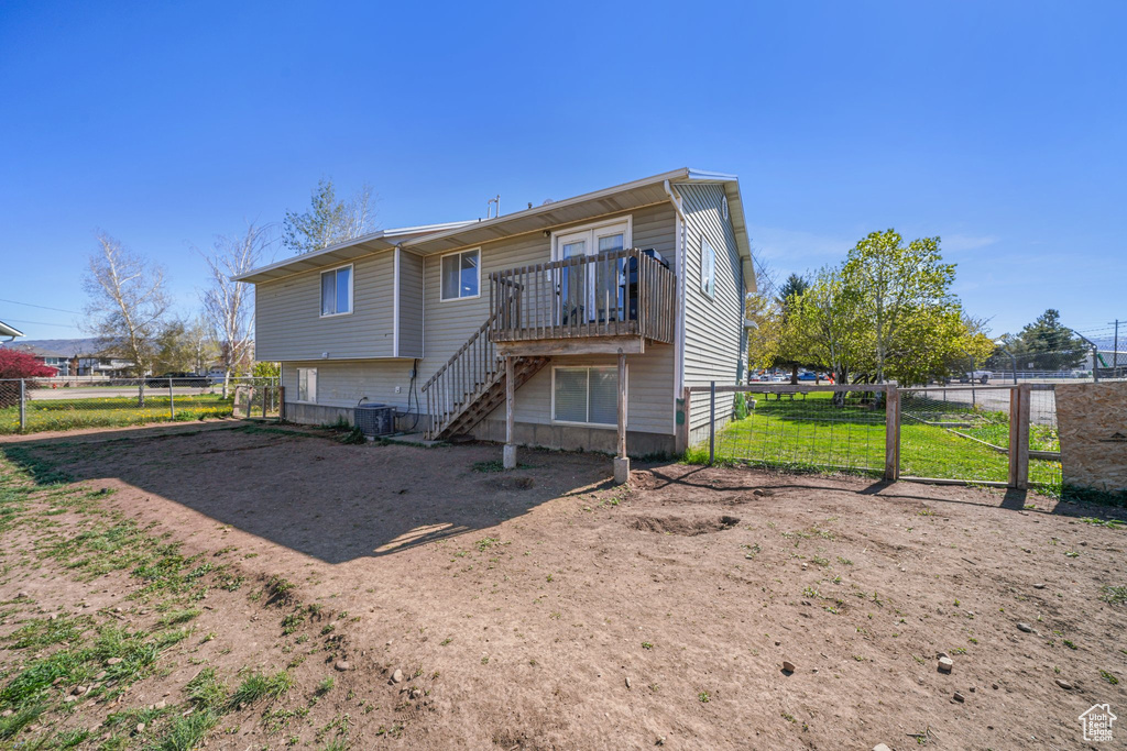 Rear view of house featuring a deck, stairs, fence, and central AC