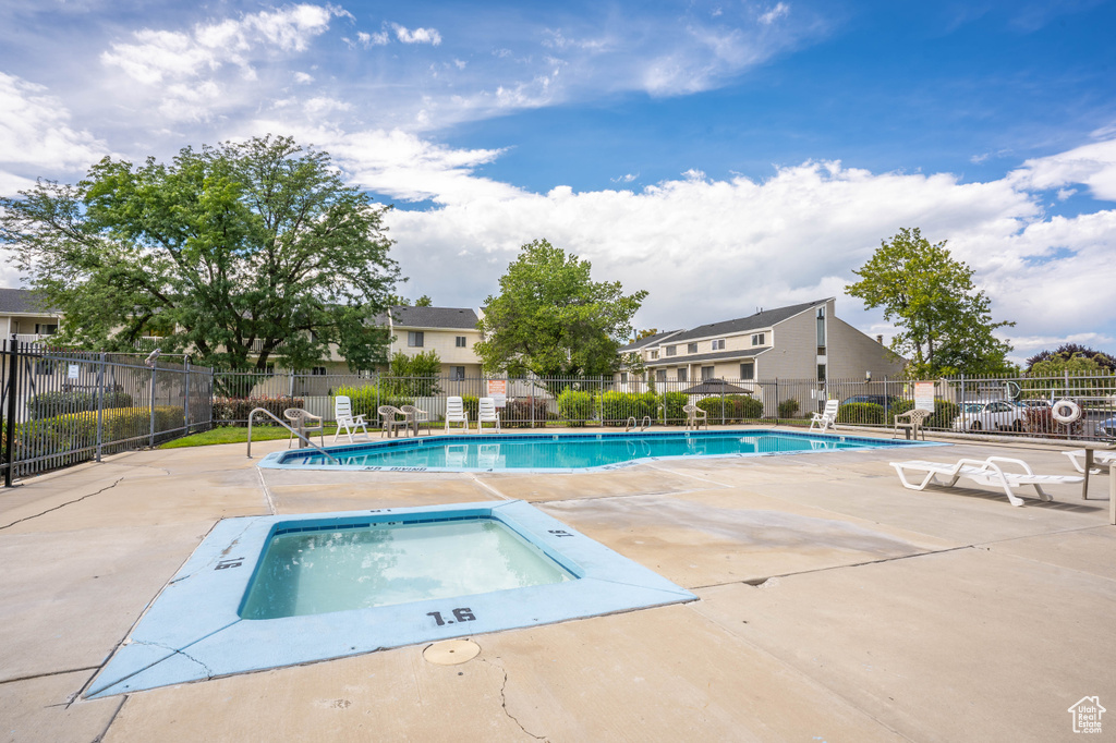 Pool featuring a hot tub, fence, a patio area, and a residential view
