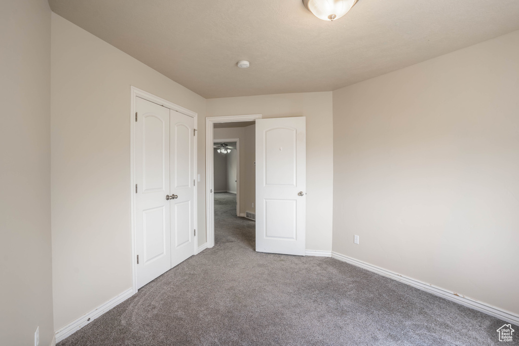 Unfurnished bedroom featuring carpet, baseboards, and a closet