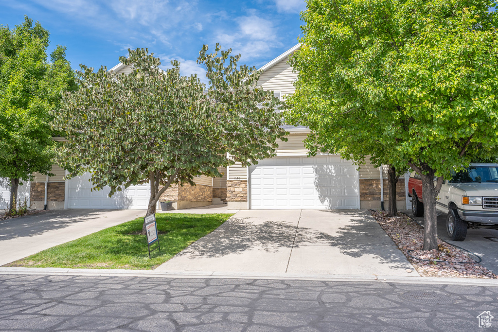Obstructed view of property with concrete driveway, stone siding, and a garage
