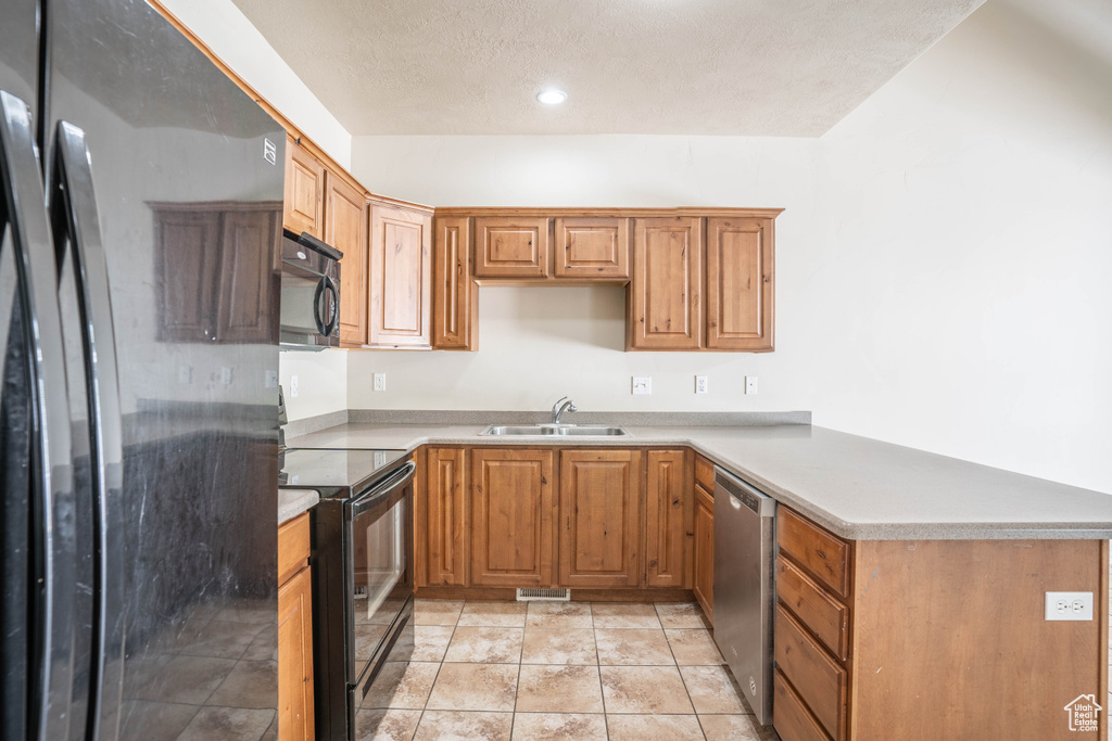 Kitchen with a peninsula, a sink, visible vents, black appliances, and light countertops