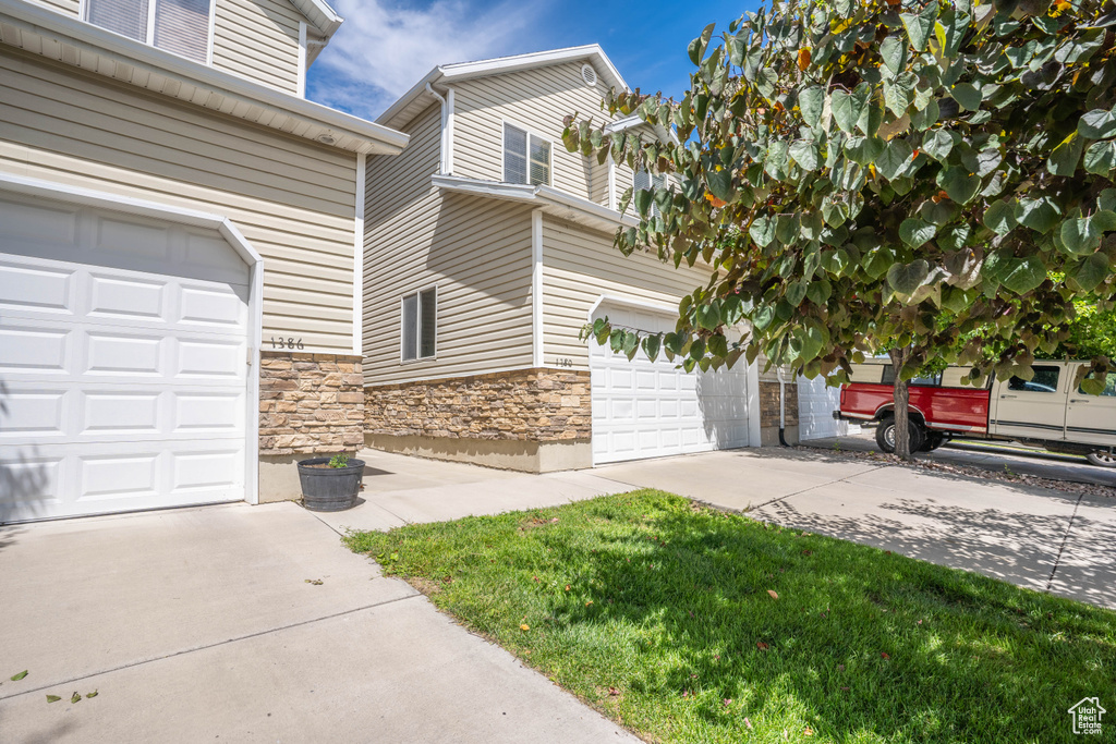 Exterior space with concrete driveway, a garage, and stone siding