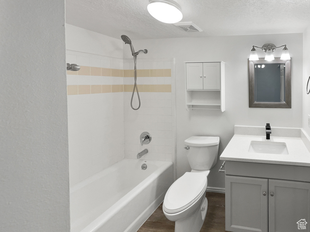 Bathroom with a textured ceiling, toilet, visible vents, vanity, and wood finished floors