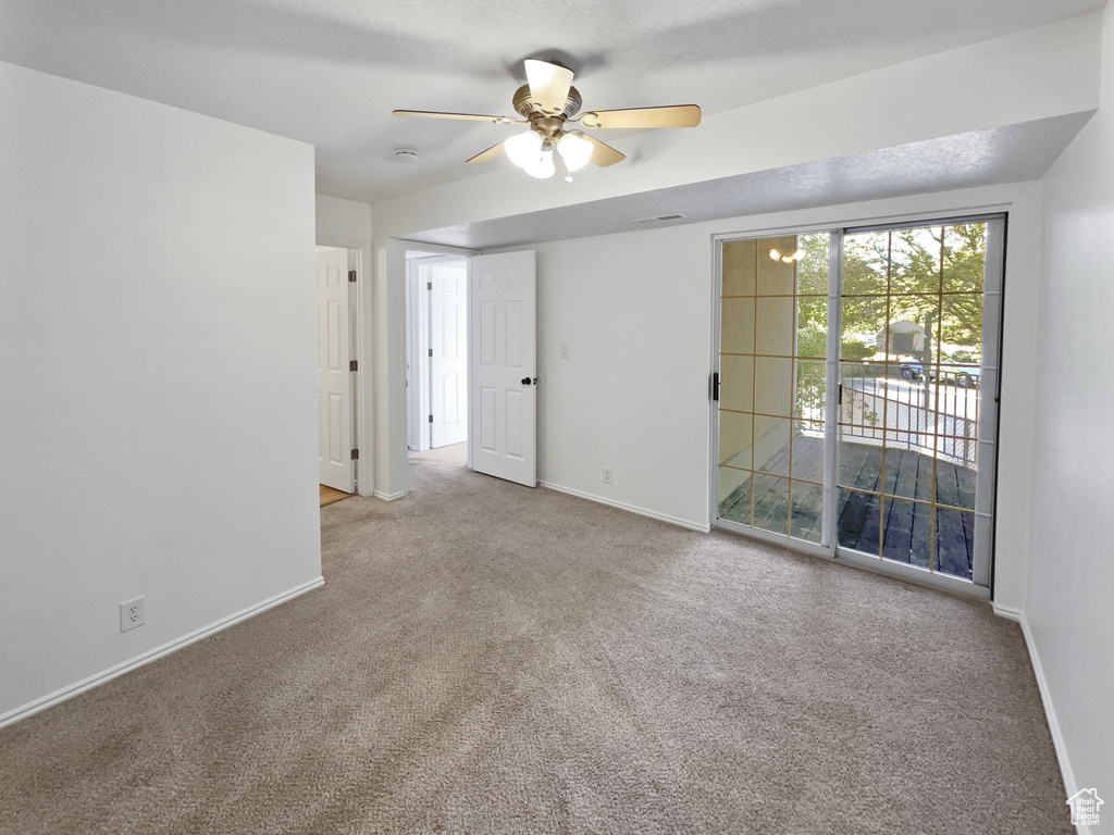 Carpeted spare room with baseboards and ceiling fan