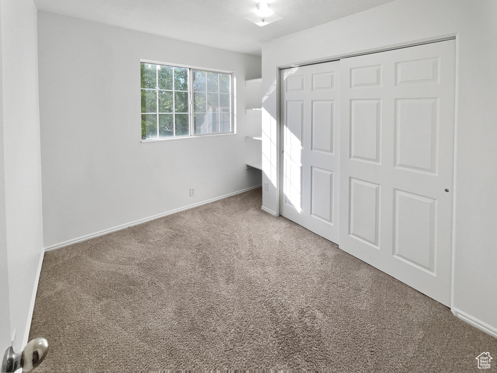 Unfurnished bedroom with carpet flooring, a closet, and baseboards