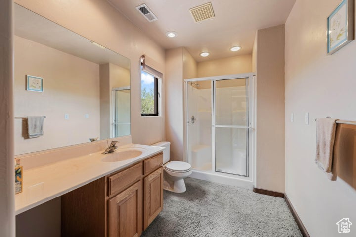 Full bathroom with a stall shower, toilet, vanity, and visible vents