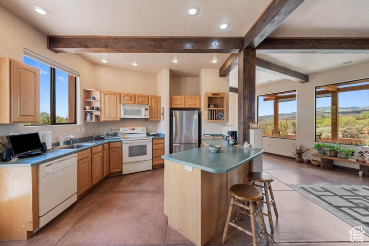 Kitchen with a breakfast bar, white appliances, a sink, open shelves, and beamed ceiling