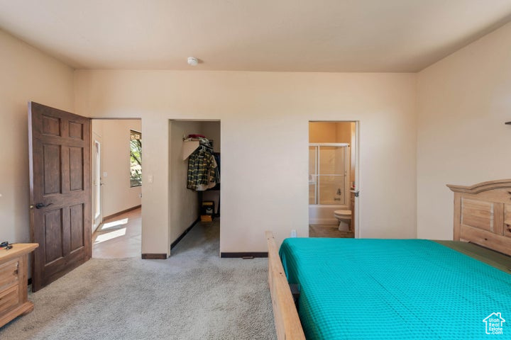 Bedroom featuring baseboards, ensuite bathroom, and light colored carpet