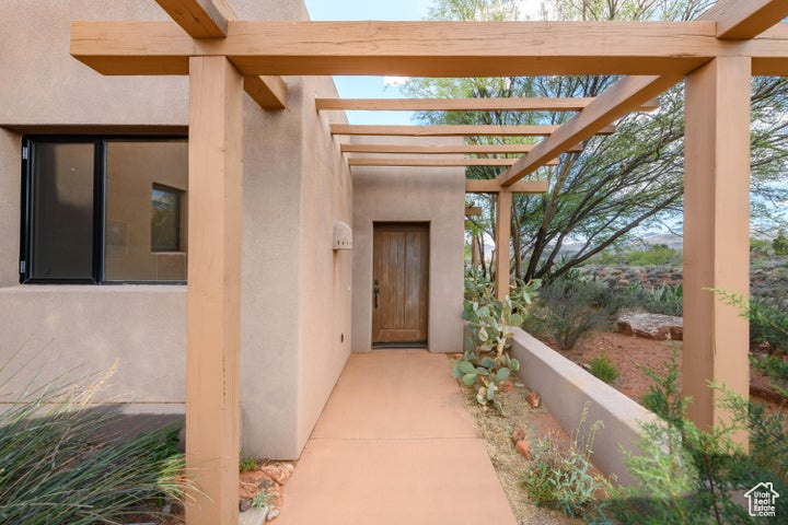 Entrance to property featuring a pergola and stucco siding