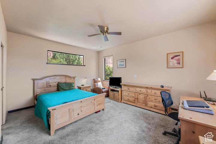 Bedroom featuring multiple windows, light carpet, and ceiling fan