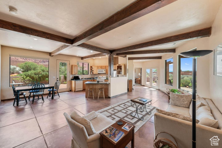 Living area featuring beamed ceiling, baseboards, light tile patterned floors, and a healthy amount of sunlight