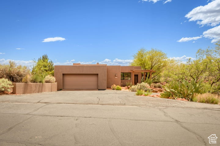Pueblo-style house featuring stucco siding, driveway, and a garage