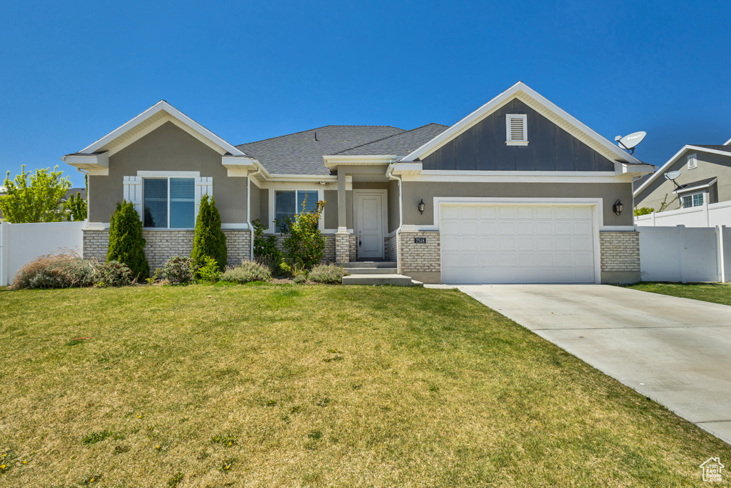 Craftsman-style house featuring an attached garage, concrete driveway, fence, and a front yard