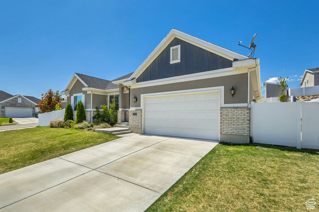 View of front of home featuring an attached garage, fence, a front yard, and board and batten siding