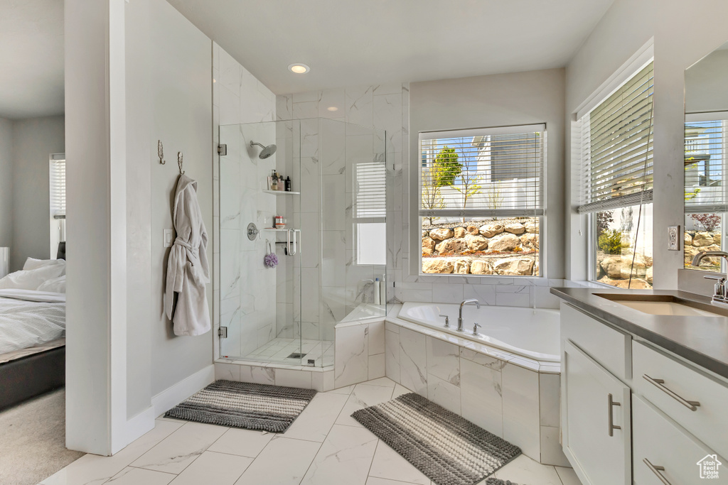 Full bath with marble finish floor, a wealth of natural light, a marble finish shower, and a garden tub