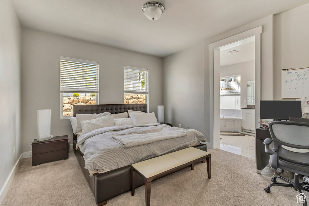 Bedroom with multiple windows, ensuite bath, and light carpet