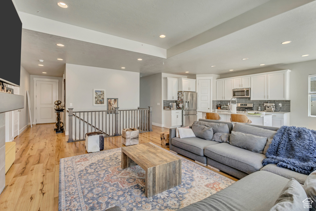 Living area featuring light wood-style flooring, baseboards, and recessed lighting