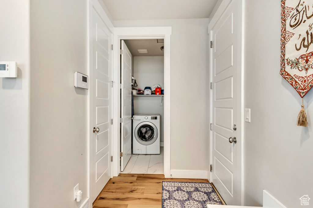 Laundry room featuring baseboards, washer / clothes dryer, laundry area, and light wood-type flooring
