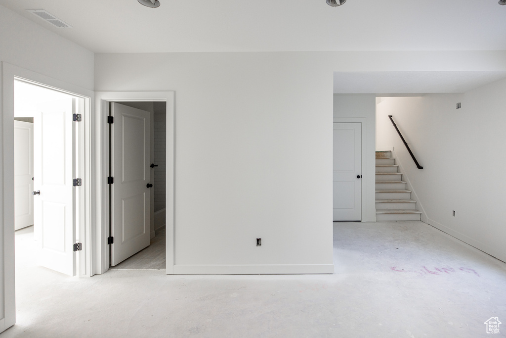 Spare room featuring stairway, baseboards, visible vents, and concrete floors