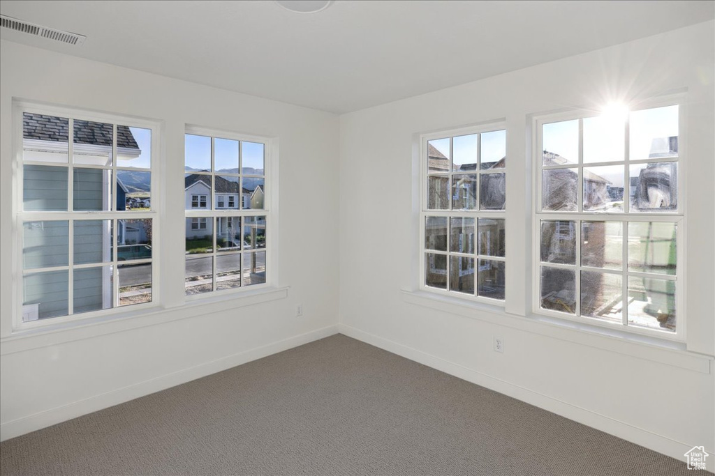Unfurnished room with dark colored carpet and baseboards