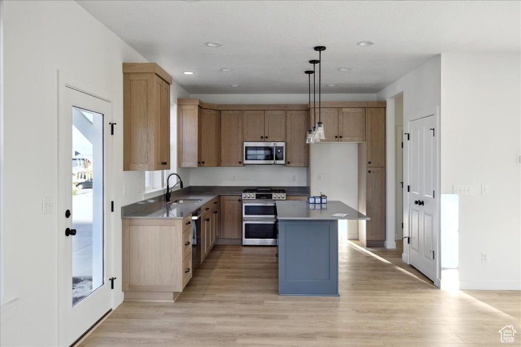 Kitchen featuring appliances with stainless steel finishes, a sink, light wood-style floors, recessed lighting, and a kitchen island