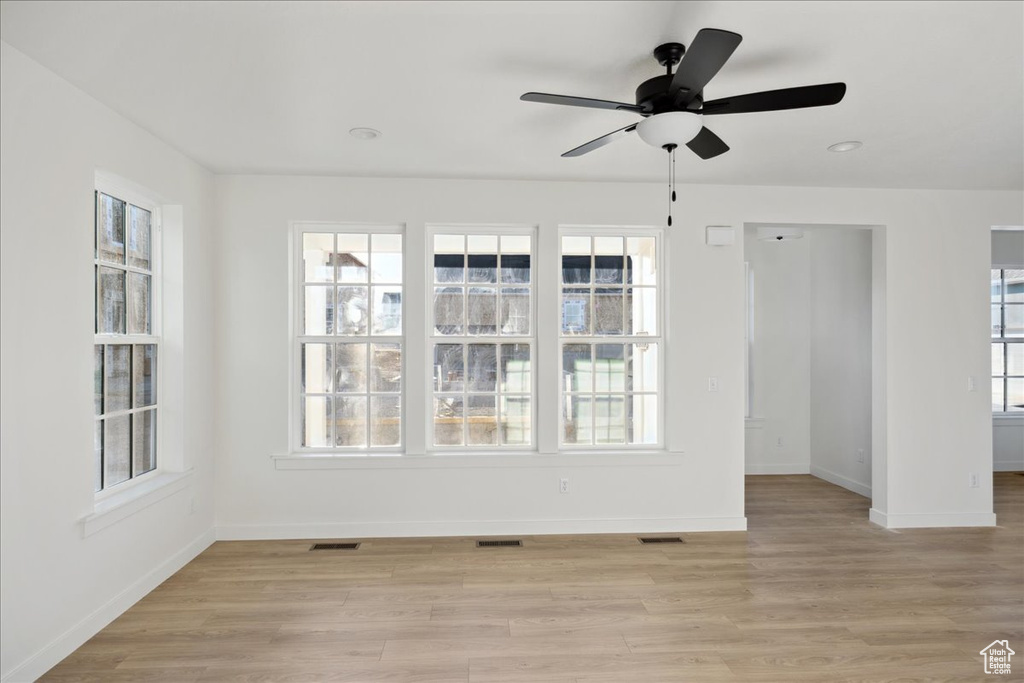 Spare room featuring baseboards, light wood-style flooring, and a ceiling fan