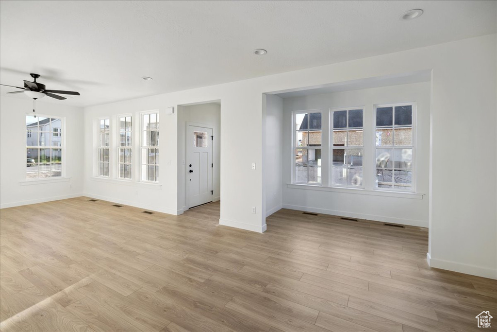 Unfurnished room with baseboards, a ceiling fan, and light wood-style flooring