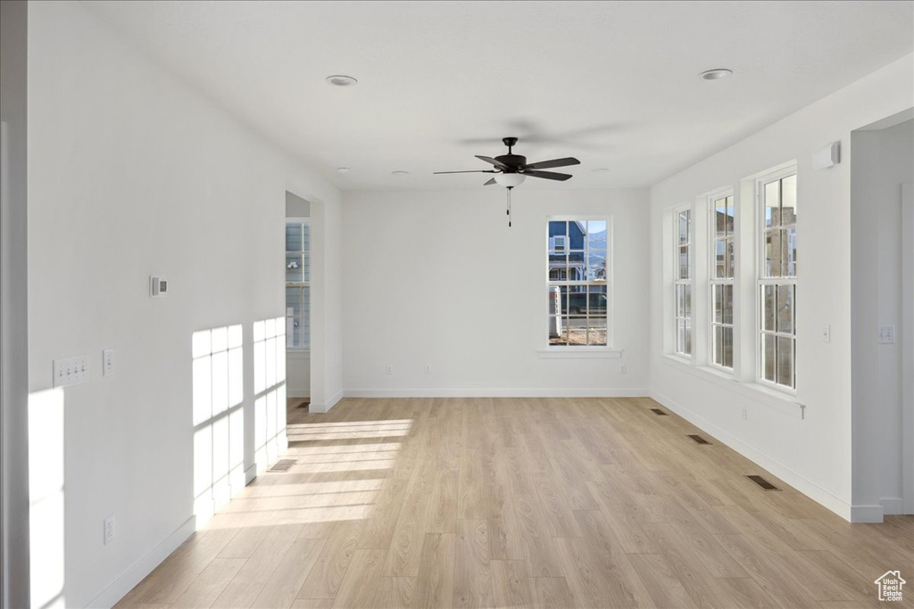 Empty room featuring light wood-style floors, baseboards, and a ceiling fan