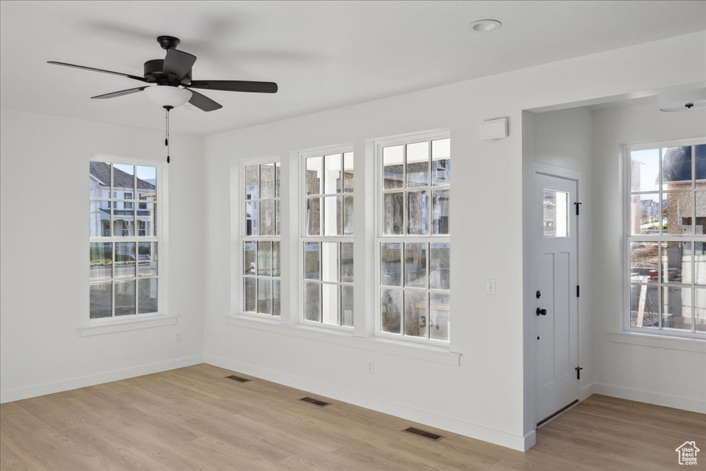 Unfurnished dining area with light wood-type flooring, ceiling fan, and baseboards