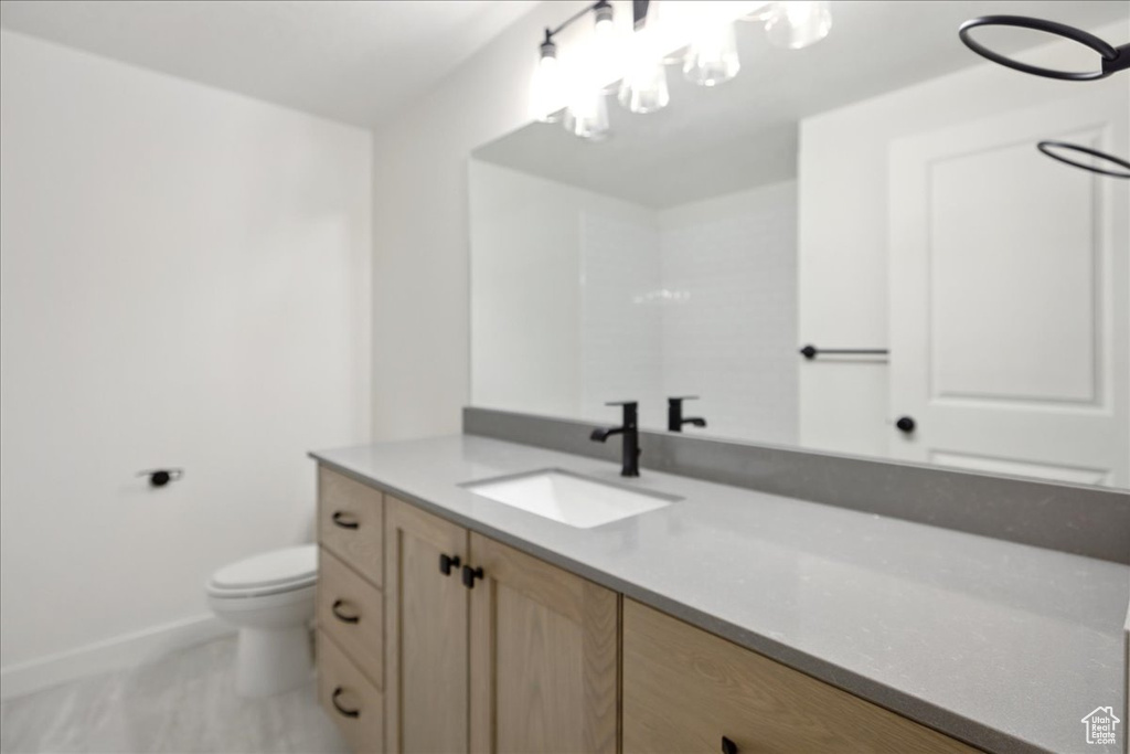Bathroom featuring vanity, toilet, and baseboards