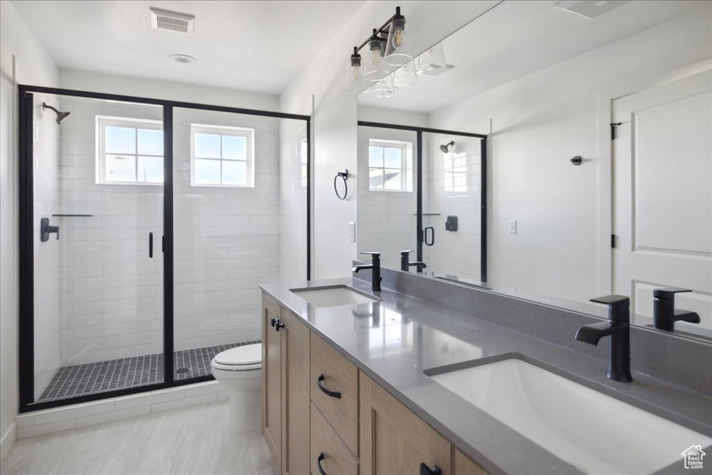 Full bathroom with toilet, double vanity, and a shower stall