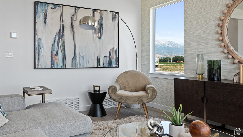 Sitting room with a mountain view, wood finished floors, visible vents, and baseboards