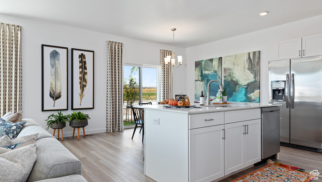 Kitchen featuring stainless steel appliances, an inviting chandelier, light wood-style flooring, light countertops, and open floor plan