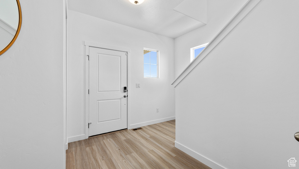 Foyer featuring light wood-style floors, visible vents, and baseboards