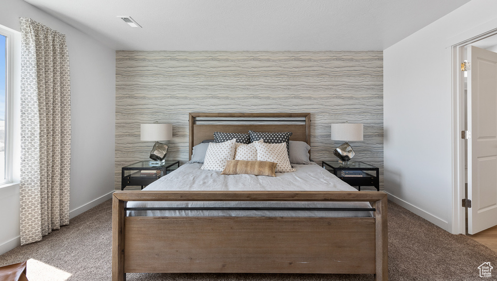 Carpeted bedroom with baseboards and an accent wall