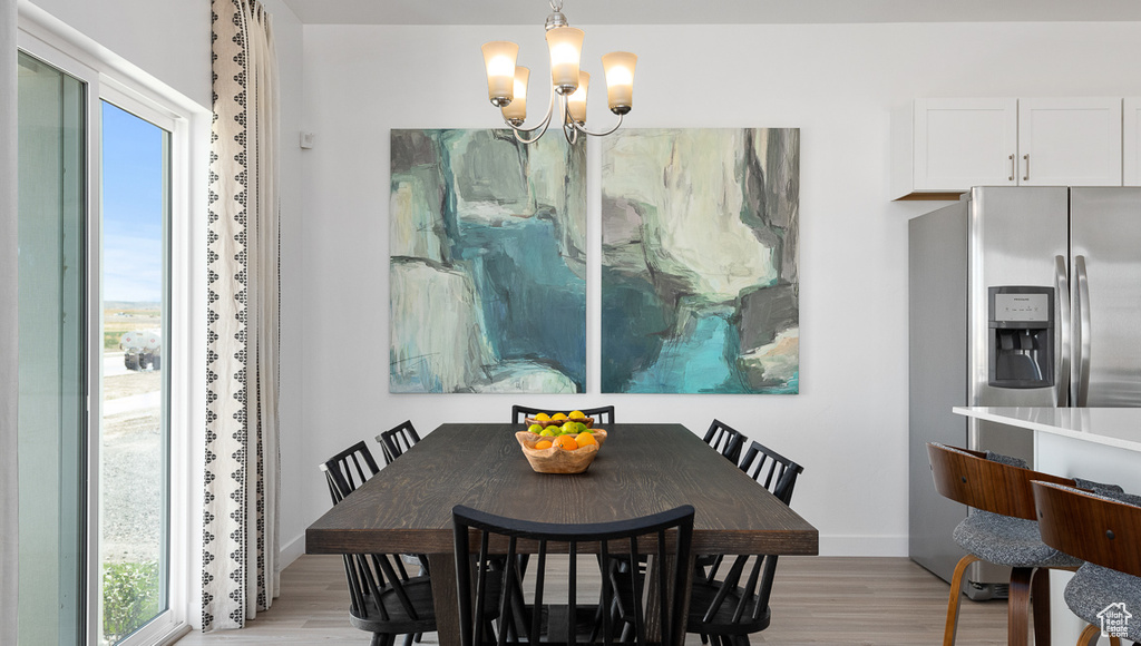 Dining area featuring light wood-style flooring, a wealth of natural light, and a notable chandelier