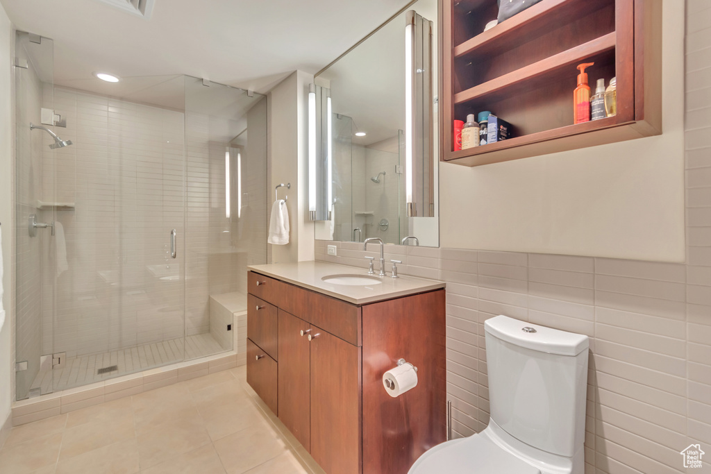 Full bath featuring toilet, tile walls, vanity, tile patterned floors, and a shower stall