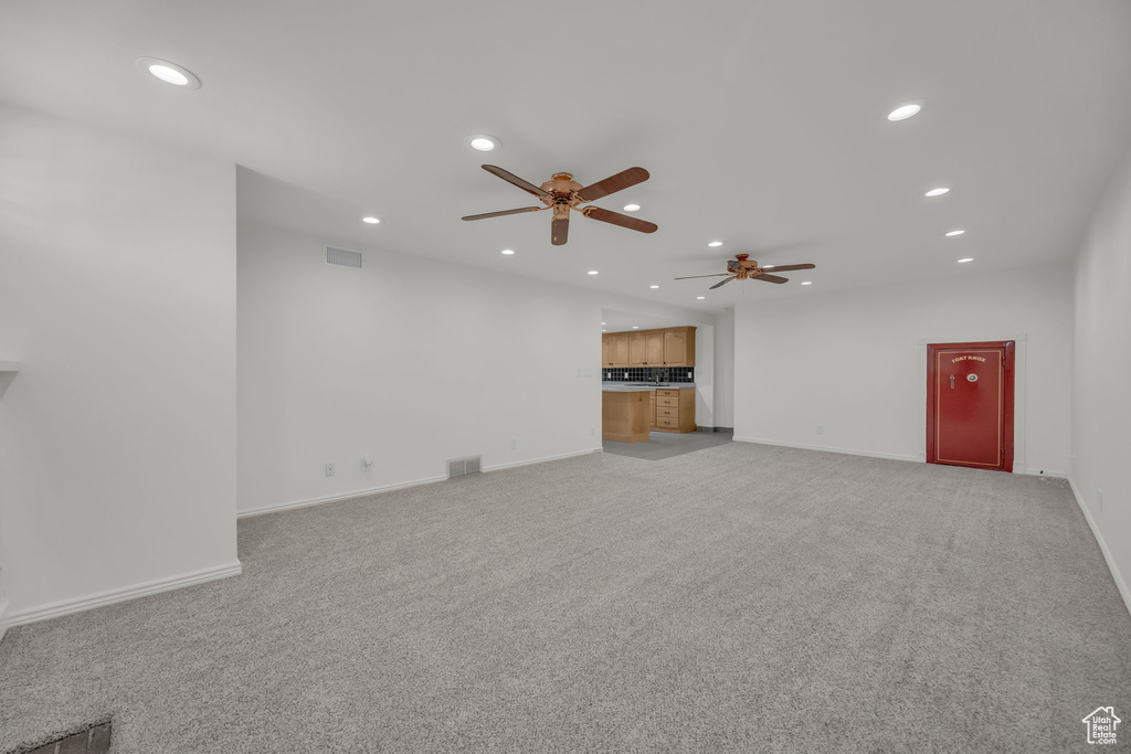 Unfurnished living room featuring recessed lighting, a ceiling fan, light colored carpet, and baseboards