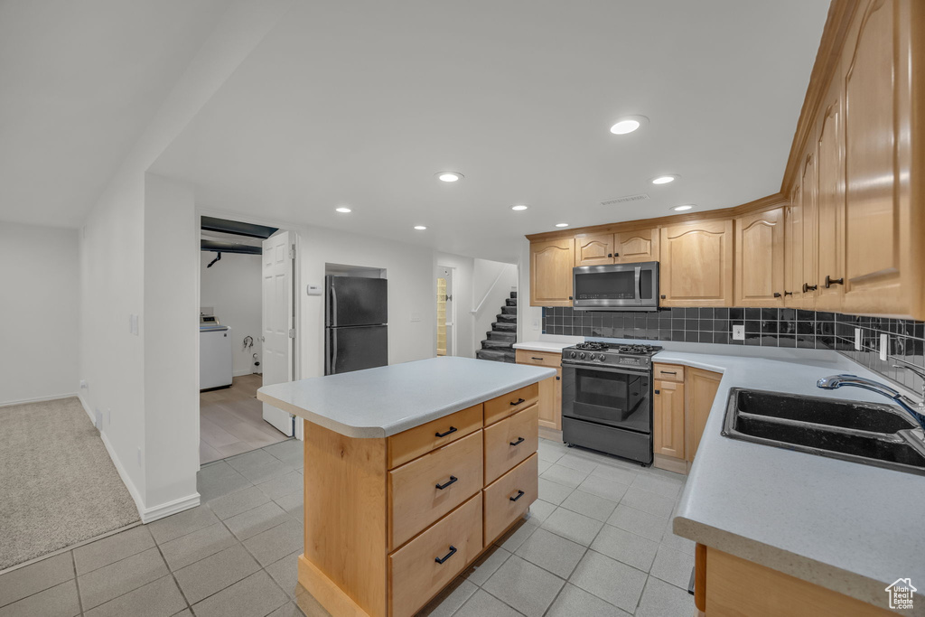 Kitchen featuring appliances with stainless steel finishes, a sink, light countertops, washer / clothes dryer, and recessed lighting