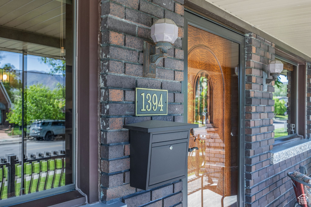 View of exterior entry featuring brick siding and a porch