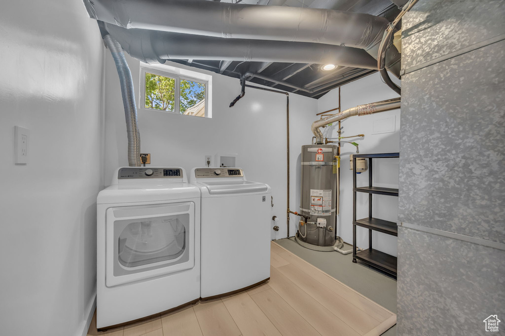 Laundry area featuring secured water heater, washer and clothes dryer, and wood finished floors