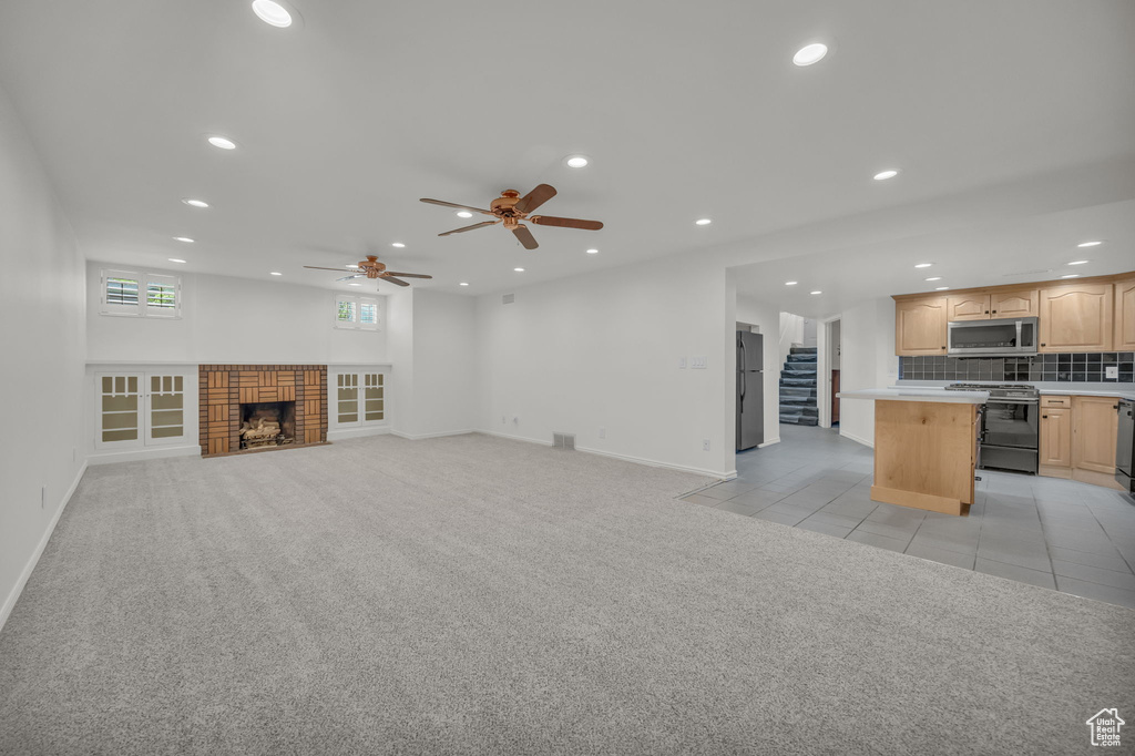 Unfurnished living room featuring recessed lighting, a ceiling fan, baseboards, stairway, and light colored carpet