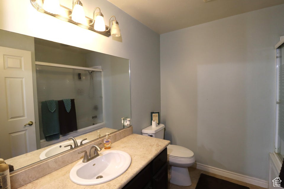 Full bath with a shower with door, toilet, baseboards, tile patterned flooring, and vanity